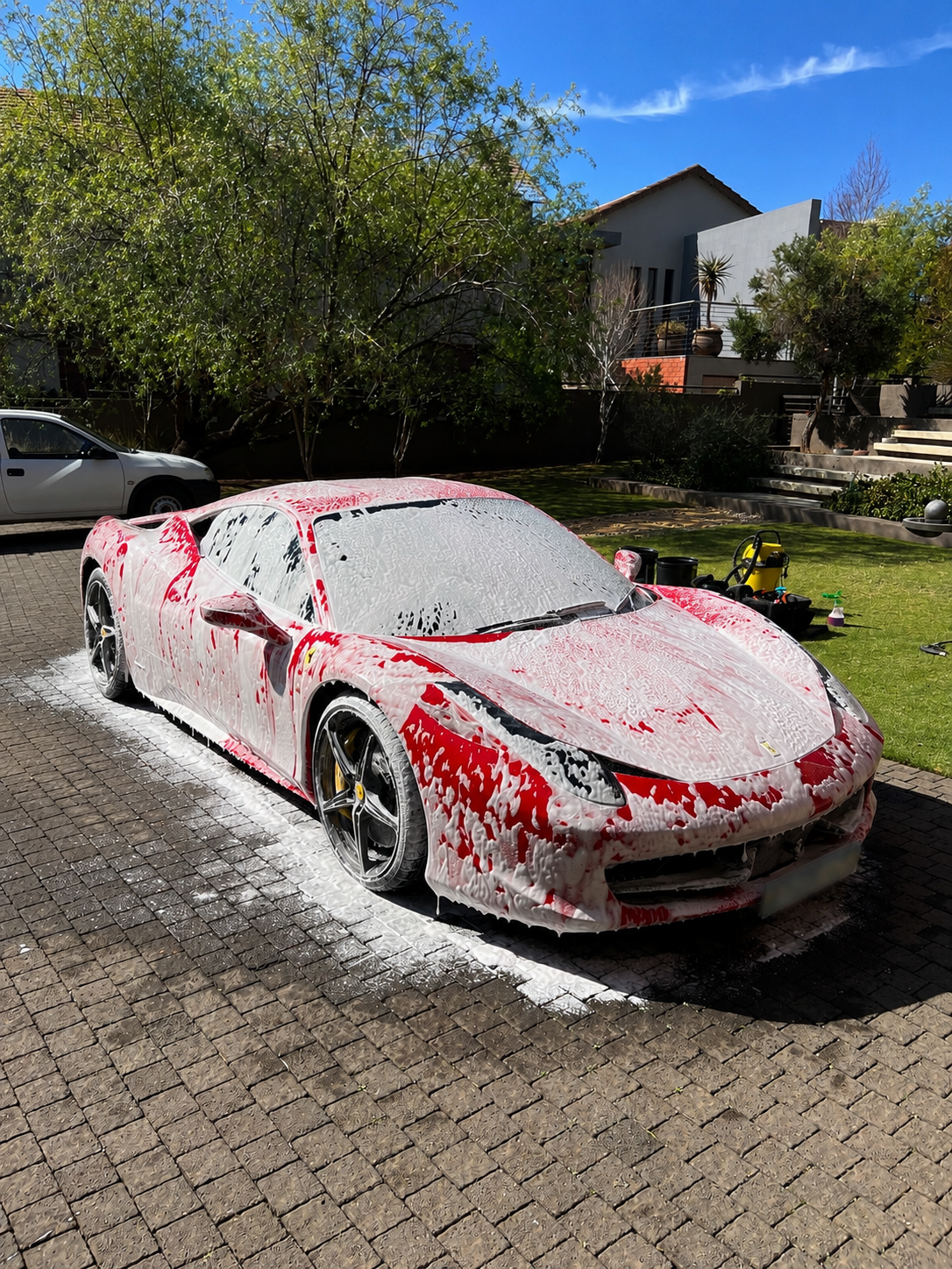 Red Ferrari 458 Italia covered in snow foam during a pre-wash